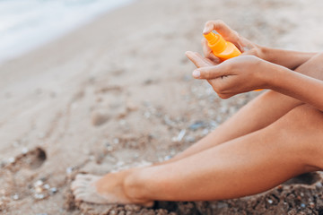 Beautiful girl, sun cream application, on the beach, feet close-up, jar of sun cream, isolated