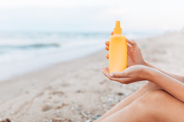 Beautiful girl, sun cream application, on the beach, feet close-up, jar of sun cream, isolated