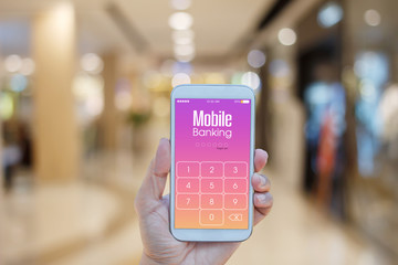 Hand holding smartphone with Mobile Banking on screen over blurred in shopping mall background