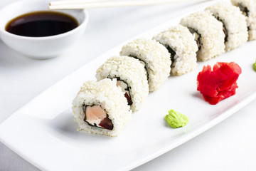 Japanese sushi rolls with salmon in rica and sesame on white background