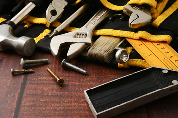 Construction worker belt with tools on wooden table background.