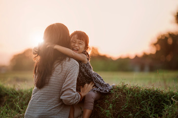 mom and kid hugging under the sunset sky