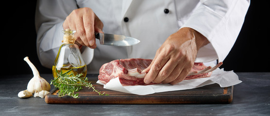 Chef cutting lamb chop with knife on wooden board