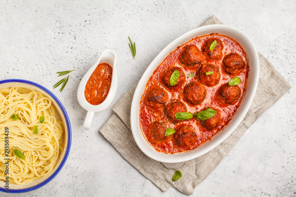 Wall mural pasta and meatballs in tomato sauce with basil in a white dish, top view.