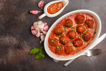 Meatballs in tomato sauce with parsley and garlic in white dish, top view, copy space.