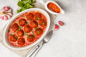 Meatballs in tomato sauce with parsley in white dish, top view, copy space.