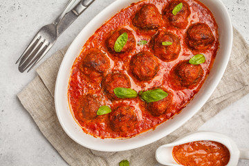 Meatballs in tomato sauce with basil in white dish, top view, copy space.