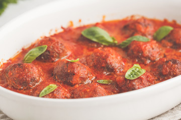 Meatballs in tomato sauce in a white dish.