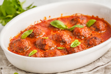 Meatballs in tomato sauce in a white dish.