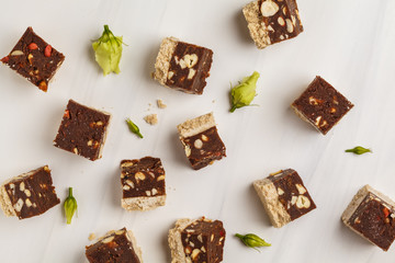 Raw vegan slices with nuts and cocoa on white background, top view. Healthy vegan food concept.