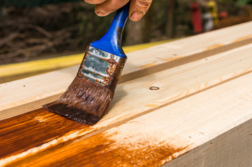 Painter with paintbrush painting wooden surface