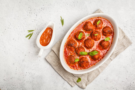 Meatballs in tomato sauce with basil in white dish, top view, copy space.