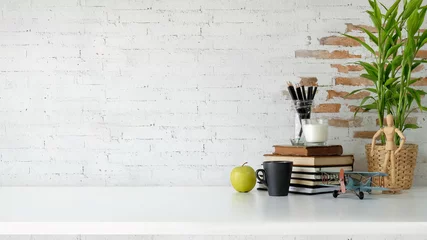 Fotobehang Per kamer Loft workspace with books, coffee mug and copy space over white brick wall.  © bongkarn