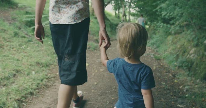 Young mother walking with toddler in nature