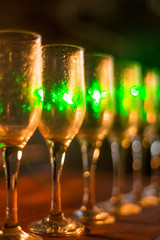 Blur abstract background interior of dark brown bar. Empty glasses for wine above a bar rack. Classic bar counter with bottles in blurred background. Interior of pub or bar at night. Luxury restaurant