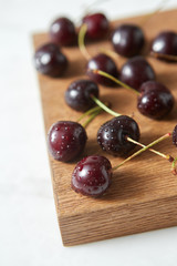 Close-up ripe sweet cherry in water droplets on a wooden board on white background with soft focus.