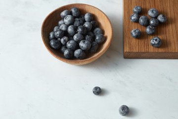 Summer organic natural sweet blueberries in a wooden plate on a white. Copy space.