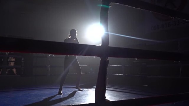 Woman is kicking in the ring. Silhouette. Slow motion