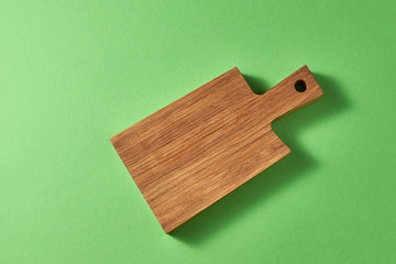 Empty wooden cutting board on a green background. Top view.