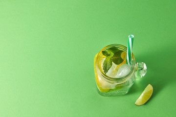 Homemade sparkling cold alcoholic mojito from natural citrus fruits with plastic straws on a green...