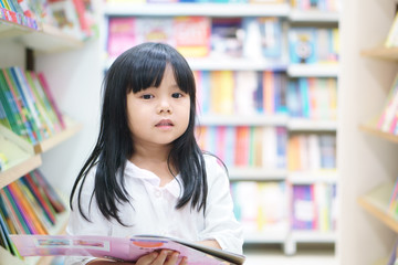 Asian children or kid girl happy smile and shopping or choose tale or story book and read on bookshelf in bookstore or library room at kindergarten school or nursery for learn and study with education