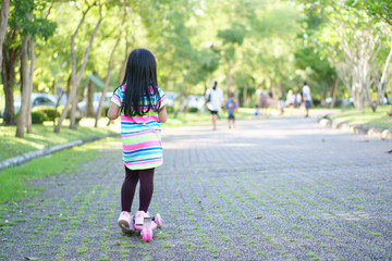 asian children or kid girl funny and playing or riding pink scooter for exercise with healthy and balance learning with training on holiday relax at public park or green garden
