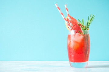 Refreshing cocktail of grapefruit with ice and rosemary on colored background of mint. Healthy citrus summer drink. 