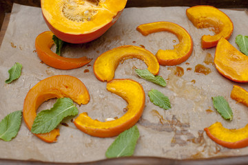 Pumpkin baked with honey and cinnamon, on a black baking sheet. Family autumn dinner. Copy space,