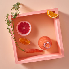 Orange detox smoothies from vegetables and fruits in a glass bottle on a yellow paper background.