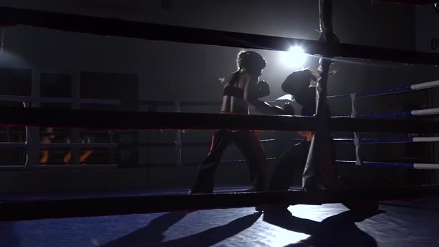 Sparring in the ring between two girls in a dark space. Slow motion