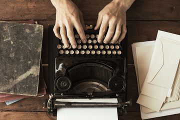 Young man's hands typing on an antique vintage typewriter - 215598683