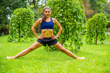 Beautiful brunette female fitness girl exercising outside in a leafy and green city park. Lady in sports top jogging in park. Healthy girl lifestyle background with copy space 