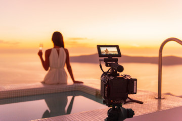 Naklejka premium Video camera filming actress woman acting for movie on luxury hotel location behind the scenes of shoot. Professional videography equipment shooting outdoor at sunset.