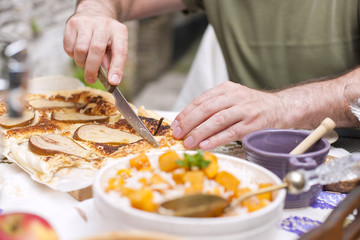 rice with pumpkin and honey on the table and other autumn food, pie with pear. Delicious family dinner in the courtyard. Men's hands in the frame. Copy space.