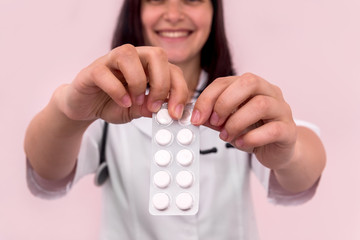 Smiling doctor taking out tablet from blister