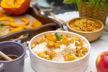 rice with pumpkin and honey on the table and other autumn food. Delicious family dinner in the courtyard. Copy space,