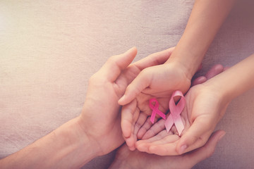Adult and child hands holding pink ribbons, Breast cancer awareness, abdominal cancer awareness and...