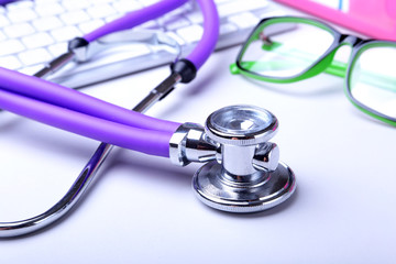 Medical record concept with stethoscope over pile of folders. Keyboard, glasses, pen, RX prescription. Selective focus