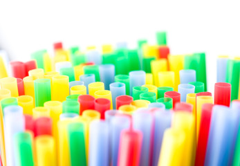 Many colourful plastic straws in a shallow depth of field and bright background
