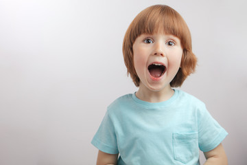ginger pleasant boy is singing the song. surprising, amazing boy with open mouth.boy is showing mouth to a doctor. copy space. child with wide open mouth