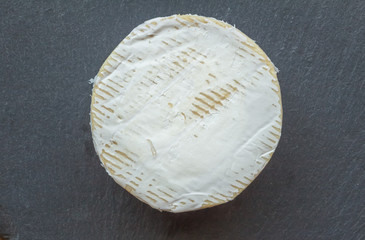 Camembert cheese isolated on black slate cheese board - Top view photo