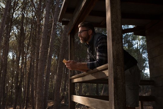 Man with mobile phone standing at cabin porch