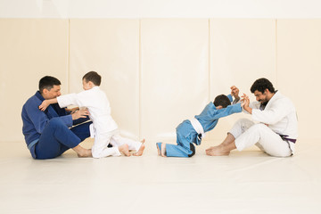 Male karate instructor training little child in dojo or jiu-jitsu at gym at tatami. Trainer teaches kid the basics of fighting for self-defense