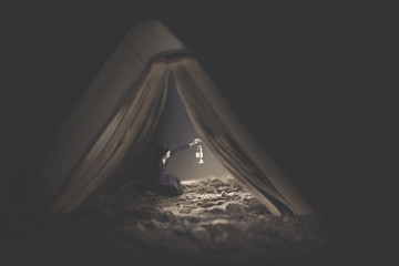 surreal image of a tiny woman who uses a book as a shelter for the night