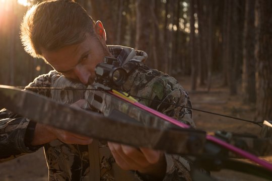 Man aiming archery in the forest with bow and arrow