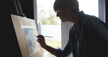 Female artist painting picture on canvas at home