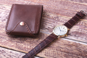 Men's accessories with brown leather wallet, belt and watch.