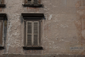 Fototapeta na wymiar Beautiful texturd wall, window shutter and street sign in Bergamo, Italy