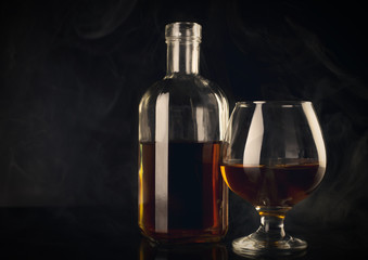 Fototapeta na wymiar cognac glass bottle smoke dark studio shot