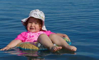 Kleinkind schwimmt auf Schwimmring im Wasser